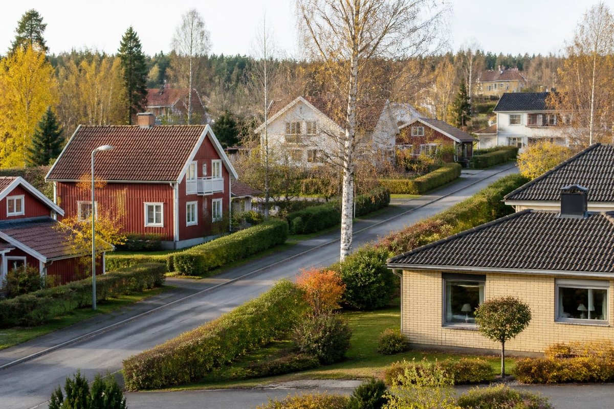 Svenskt villaområde med röda trähus, gult tegelhus och björkar en höstdag
