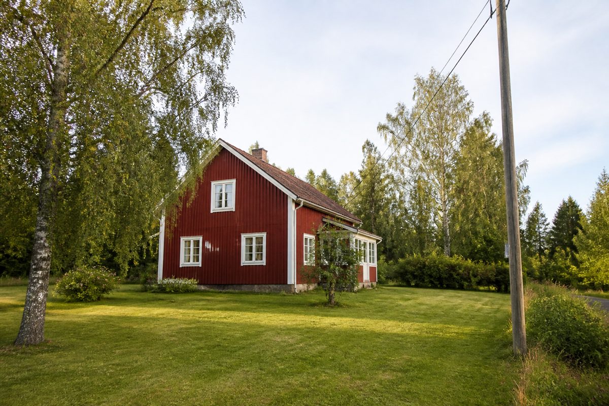 Röd faluröd villa på en lantlig tomt med björkar och en trästolpe med elledningar – ledningsrätt